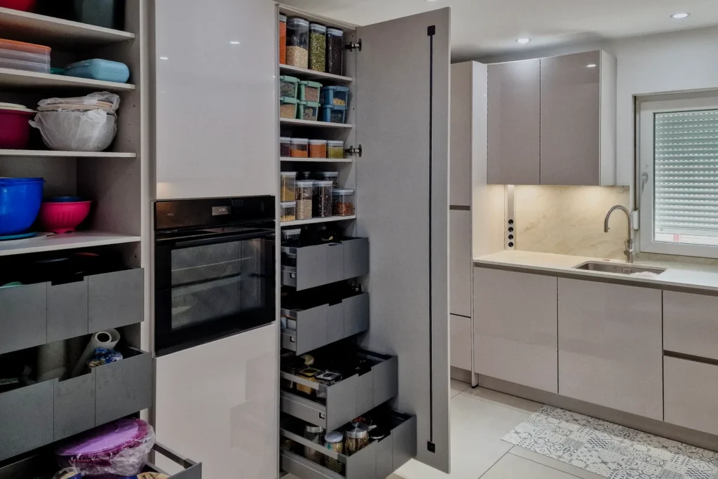 Einbauküche mit Hochschrank, Auszügen und Backofen sowie Spülbecken mit Armatur und hellem Unterschrank.
