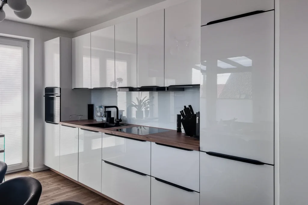 Moderne Einbauküche mit weißem Schrankfronten, dunkler Arbeitsplatte, integriertem Kochfeld und hoher Schubladenfront