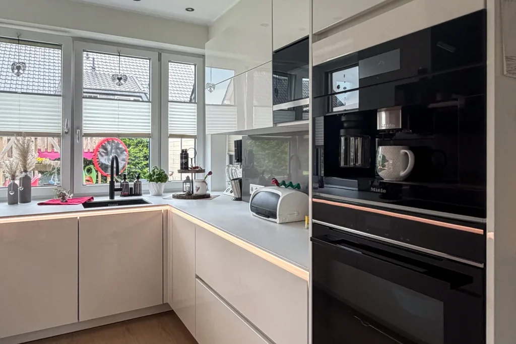 Moderne Einbauküche mit Spüle, Arbeitsplatte und eingebautem Ofen mit Beschriftung „Miele“