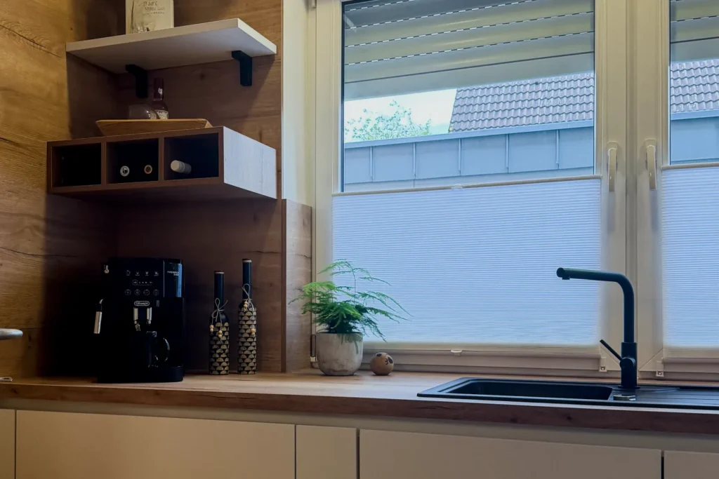 Küchenarbeitsplatte mit Spüle, Armatur und integrierten Ablagen mit Kaffeegerät vor Fenster