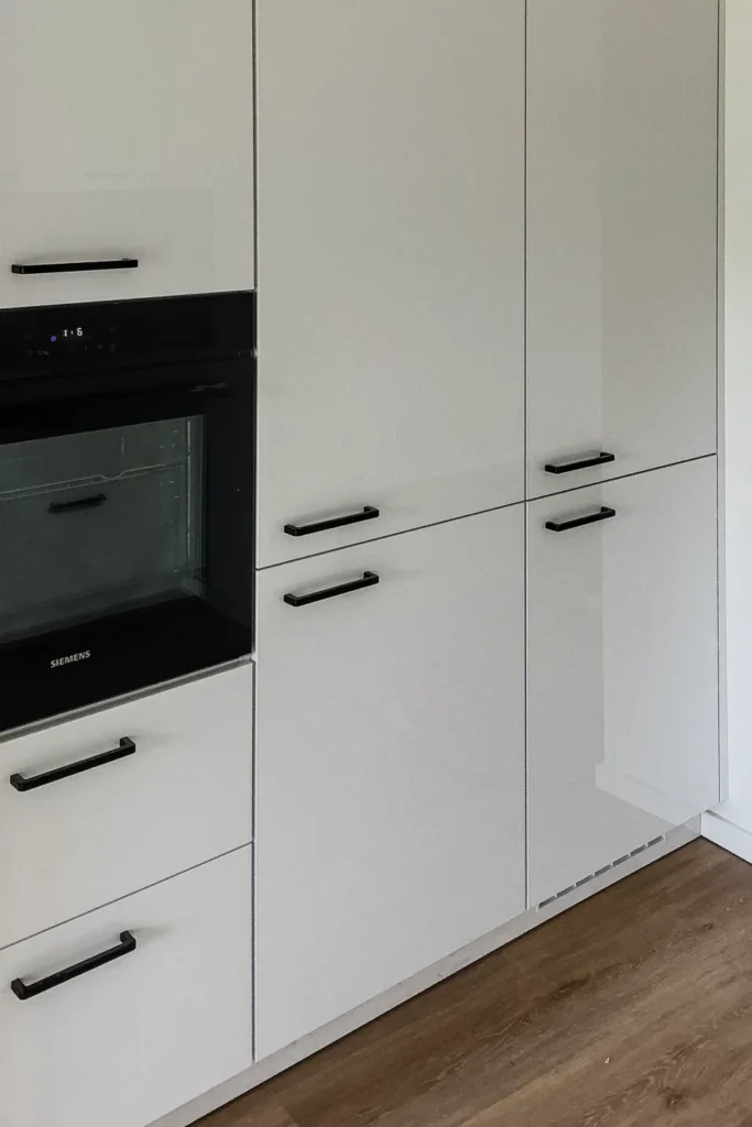 Weiße Küchenzeile mit Backofen, Schubladen und Griffleisten an den Fronten