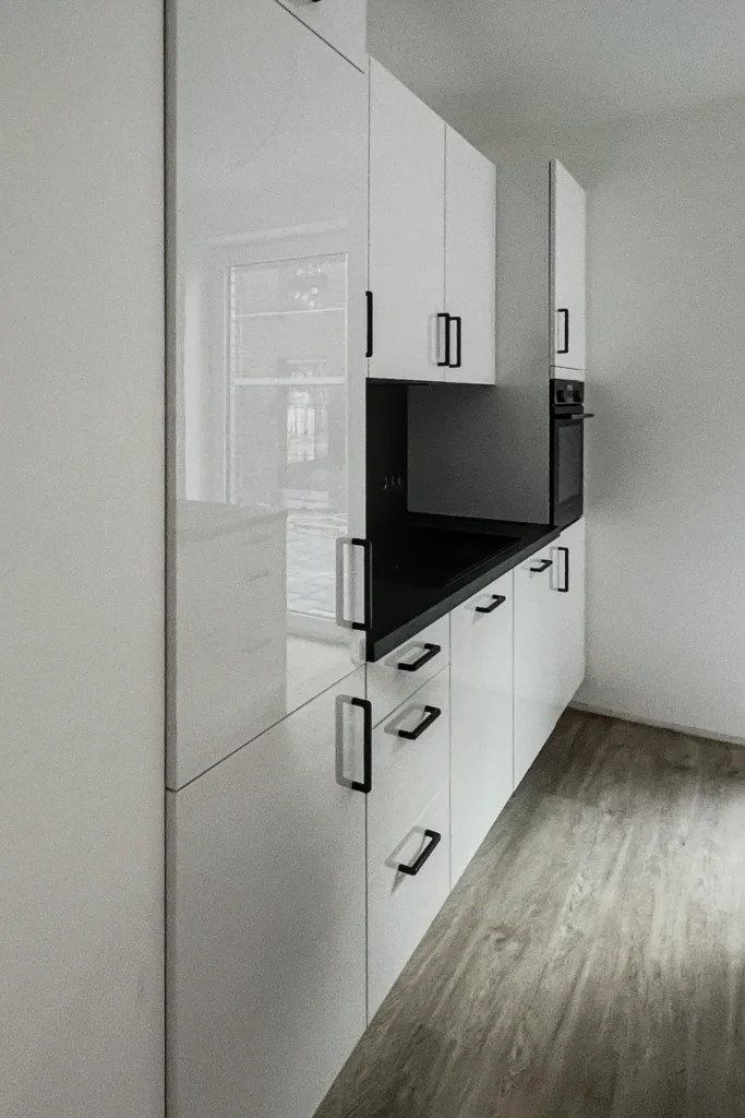 Weiße Küchenzeile mit Hochschrank, Schubladen und integriertem Spül-/Kochbereich, seitlich geöffnet