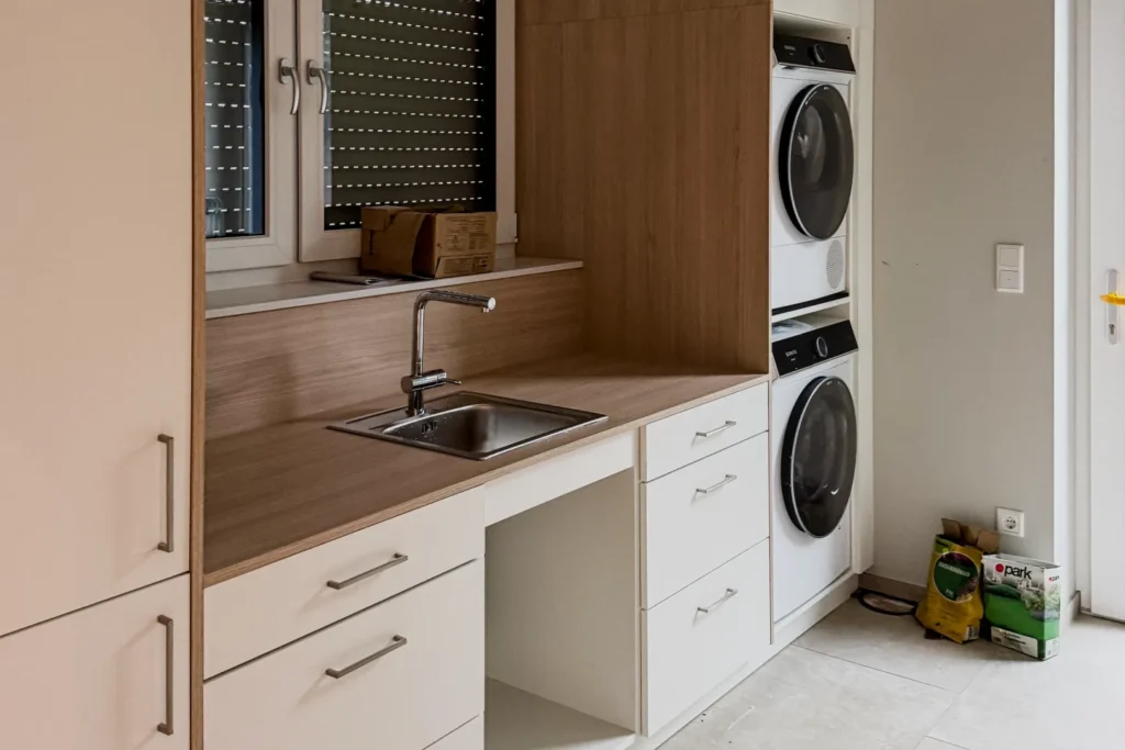 Moderne Küchenzeile mit Spüle, Armatur, Backofen und Geschirrspüler in Holz- und Weißfronten