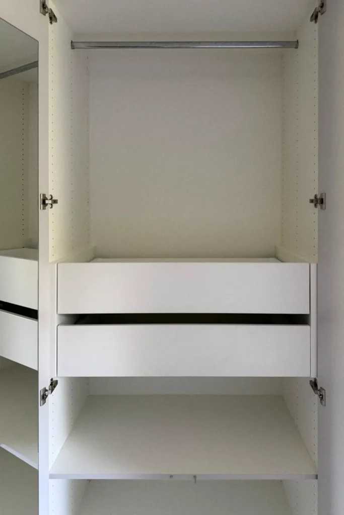 Innenansicht eines weißen Küchenunterschranks mit ausziehbaren Schubladen und Regalfach