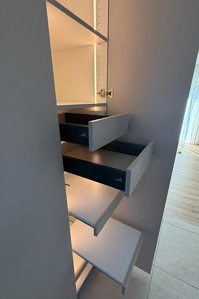 Geöffneter Hochschrank mit ausziehbaren Schubkästen und Beschriftung „Hettich“.