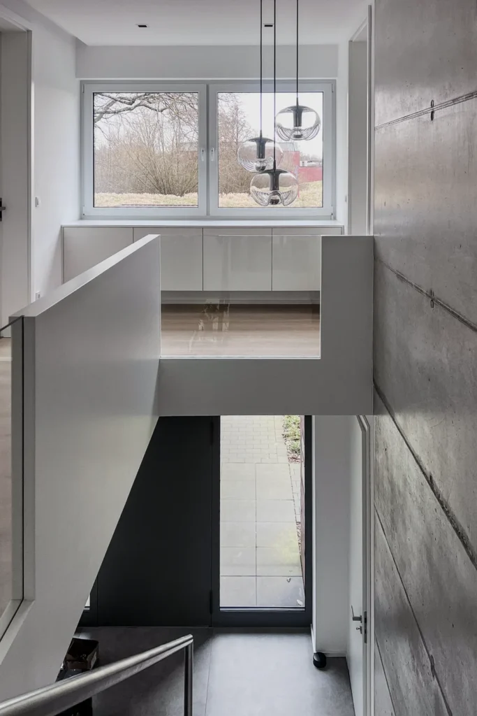 Offene Kücheninsel mit Schubladen, große Fensterfront und Hängelampen im modernen Küchenraum.