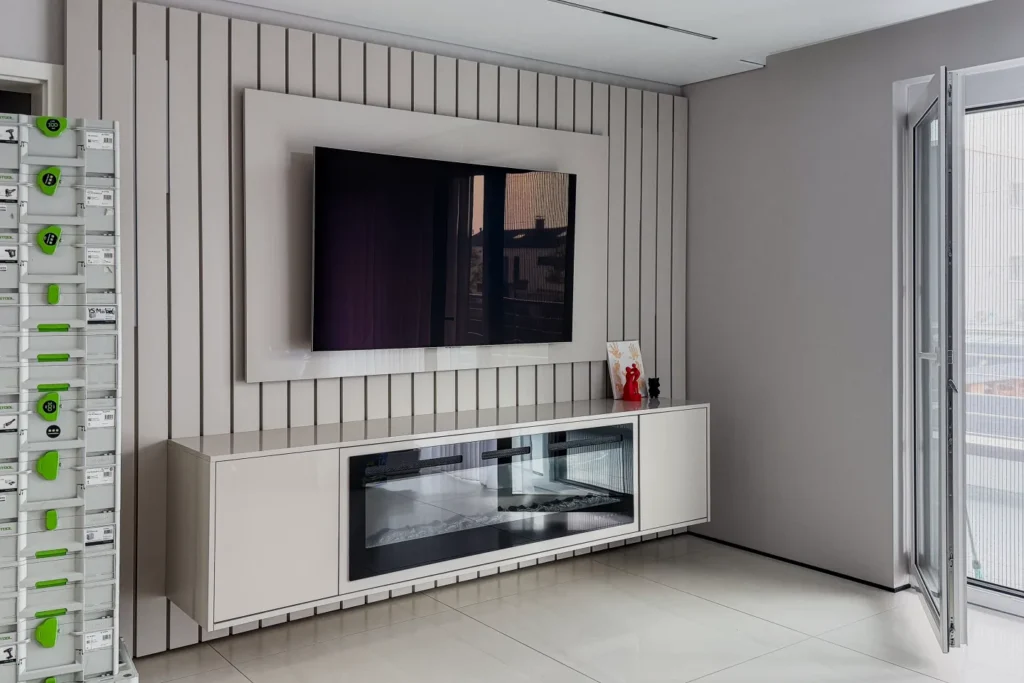 TV-Wand mit Einbauschrank und geschlossener Glastür darunter, daneben Terrassentür im hellen Raum
