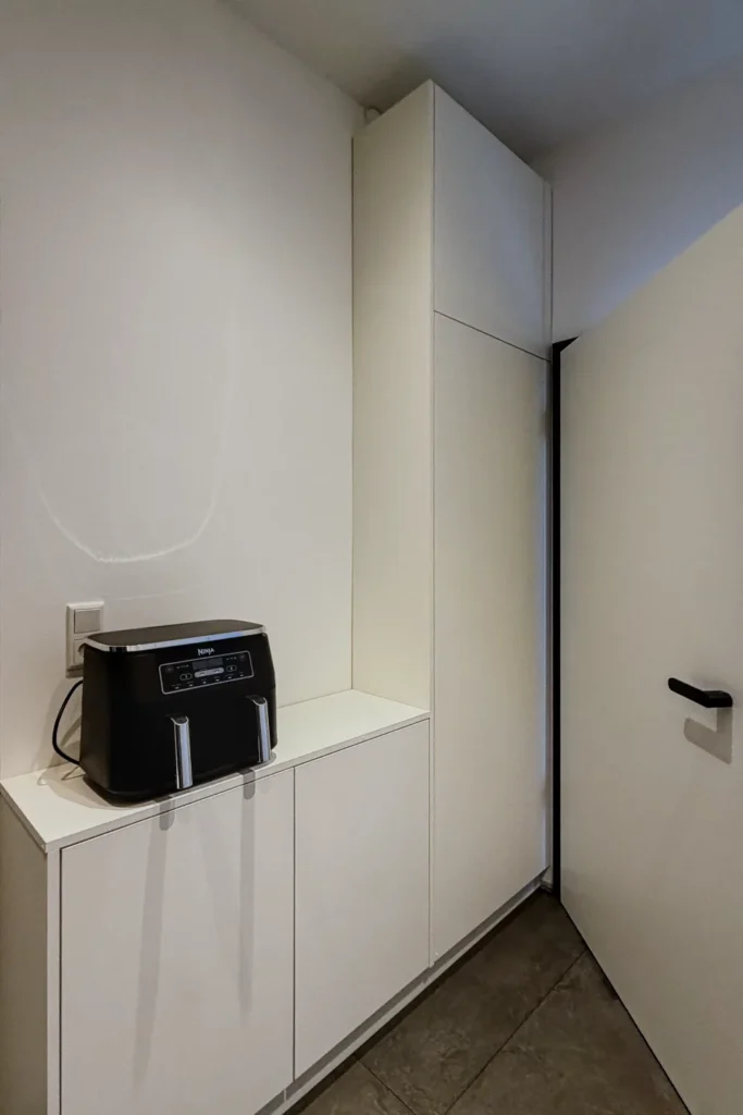 Küchenzeile in der Ecke mit weißem Schrank und Kaffeemaschine („NOVA“) auf der Arbeitsplatte