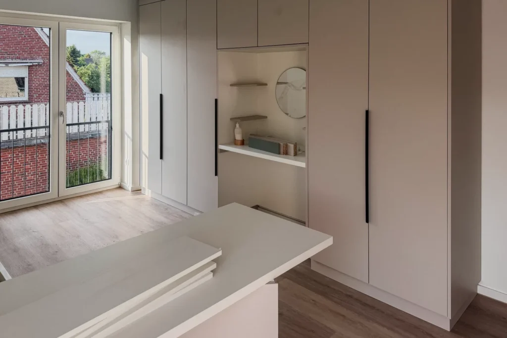 Moderne Einbauküche mit hoher Schrankwand, Nischenregal und hellem Arbeitsbereich neben dem Fenster