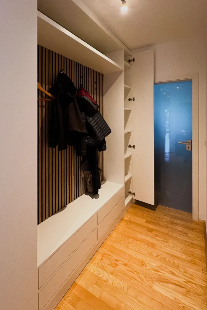 Einbauschrank im Flur mit Garderobenbereich, Fächern, hängenden Jacken und Holzlaminatboden