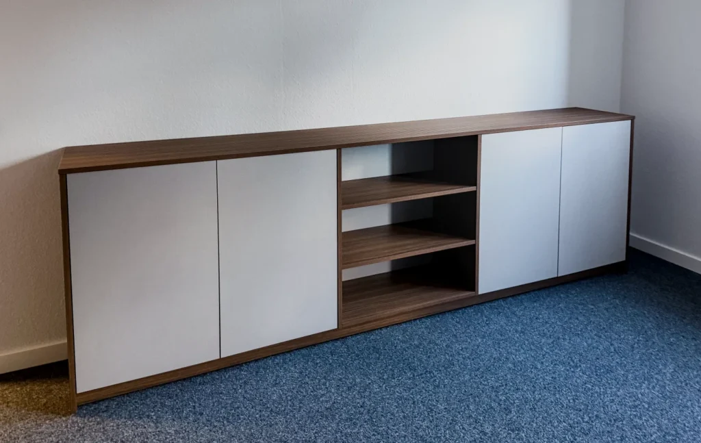 Sideboard mit Holzplatte, zwei Schranktüren und offenen Regalfächern, weiß-braunes Möbelstück in heller Ecke