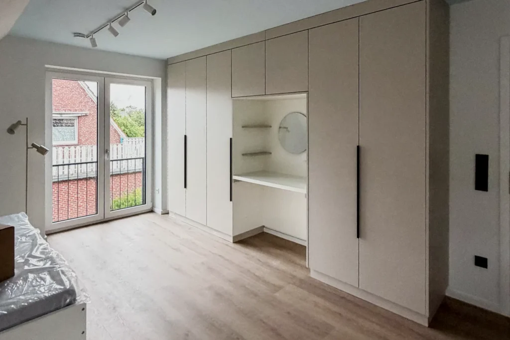 Einbauküche mit hohen Schrankfronten und geöffnetem Nischenregal, Holzboden und große Fensterfront im Raum