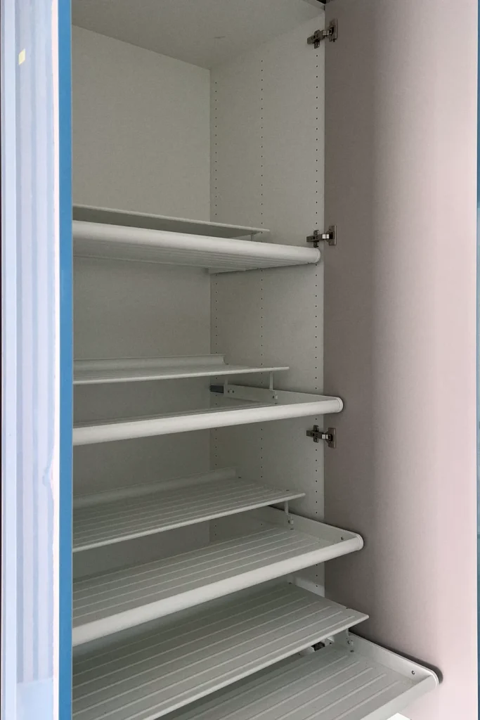 Einbauschrank mit gelochten Seitenwänden und mehreren Drahtböden, geöffnet