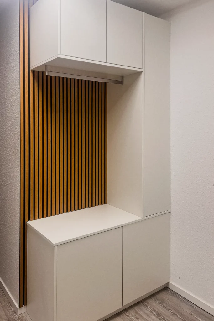 Einbauschrank mit offenem Stauraum und Fensterbank, darunter Schubladen, darüber Hochschrank mit Klappe und Lamellenfront.