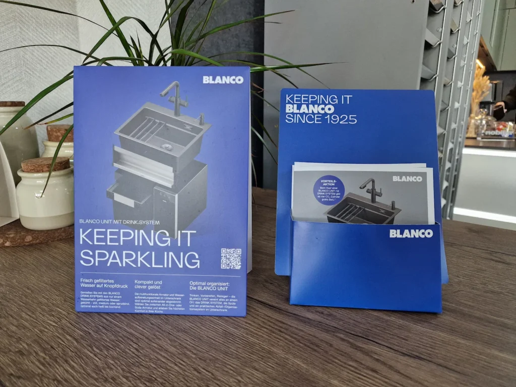 Zwei blaue BLANCO-Produktverpackungen mit „KEEPING IT SPARKLING“, „KEEPING IT BLANCO SINCE 1925“ und Armaturabbildung
