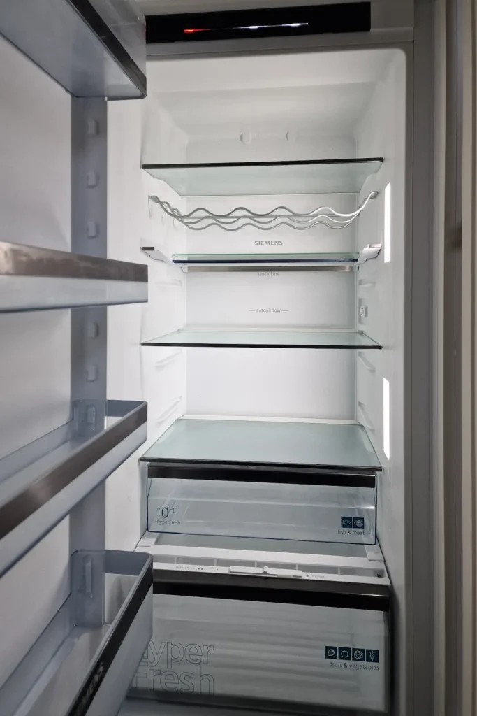 Innenansicht eines Kühlschranks mit offenen Schubfächern, „SIEMENS“, „hyperFresh“, „fish & meat“ und „fruit & vegetables“