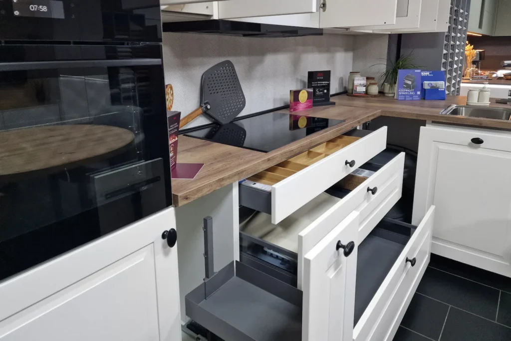 Küchenzeile mit Backofen, Herdfläche und offenem Schubladenschrank auf Holz-Arbeitsplatte